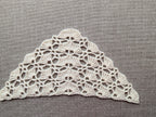 Close-up shot of intricate lace stitches and openwork mesh texture on a crochet bandana shawl.