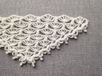 Close-up shot of intricate lace stitches and openwork mesh texture on a crochet bandana shawl.