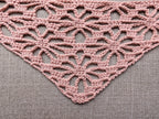 Close-up shot of intricate lace stitches and openwork mesh texture on a crochet bandana shawl.