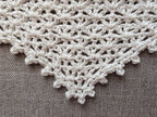 Close-up shot of intricate lace stitches and openwork mesh texture on a crochet bandana shawl.