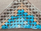 Close-up shot of intricate lace stitches and openwork mesh texture on a crochet bandana shawl.