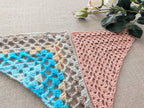 Close-up shot of intricate lace stitches and openwork mesh texture on a crochet bandana shawl.