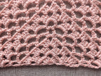 Close-up shot of intricate lace stitches and openwork mesh texture on a crochet bandana shawl.