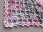 Close-up shot of intricate lace stitches and openwork mesh texture on a crochet bandana shawl.