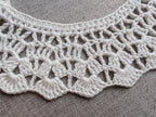 Close-up shot of intricate lace stitches and delicate openwork mesh texture on a crochet collar.