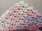 Close-up shot of intricate lace stitches and openwork texture on a curved half-circle crochet baktus.