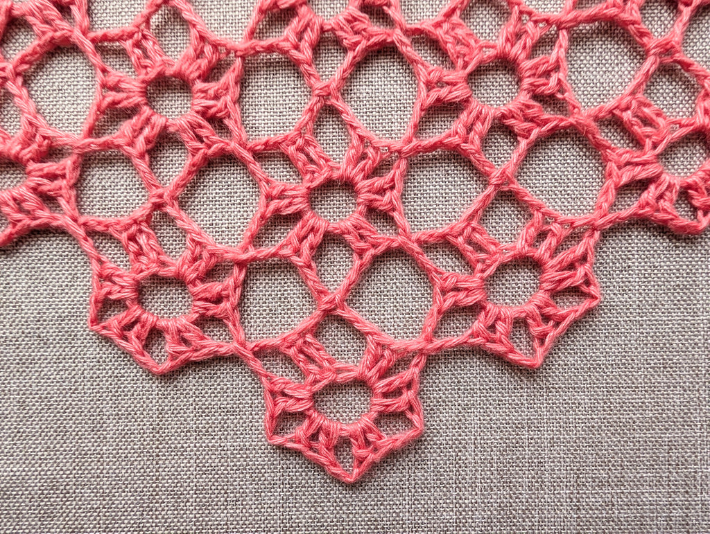 Close-up shot of continuous motif lace stitches and intricate texture on a crochet shawl.
