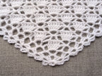 Close-up shot of intricate lace stitches and openwork mesh texture on a crochet baktus shawl.