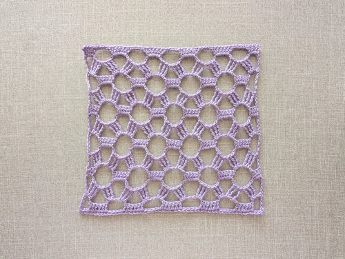 Close-up shot of intricate lace stitches and openwork mesh texture on a rectangle crochet scarf.
