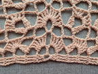 Close-up shot of intricate lace stitches and openwork mesh texture on a crochet bandana shawl.