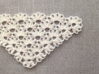 Close-up shot of intricate lace stitches and openwork mesh texture on a crochet bandana shawl.