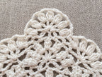 Close-up shot of intricate lace stitches and openwork mesh texture on a crochet bandana shawl.