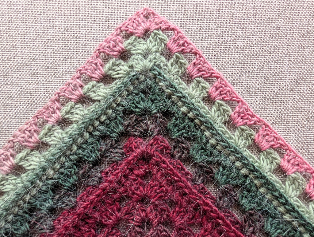 Flat lay of Chart 113 crocheted kerchief bandana variation in cake yarn with shell lace edges.