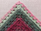 Flat lay of Chart 113 crocheted kerchief bandana variation in cake yarn with shell lace edges.