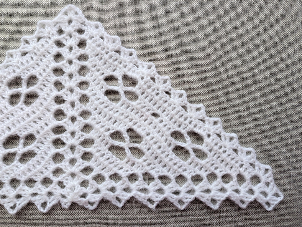 Close-up detail of filet crochet flower pattern showing double crochet stitch placement and decorative scalloped border.