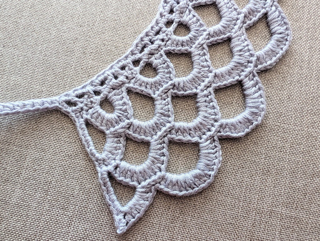 The front view of the textured crochet lace accessory, illustrating how the scalloped bottom edge and openwork pattern sit perfectly flat against clothing.