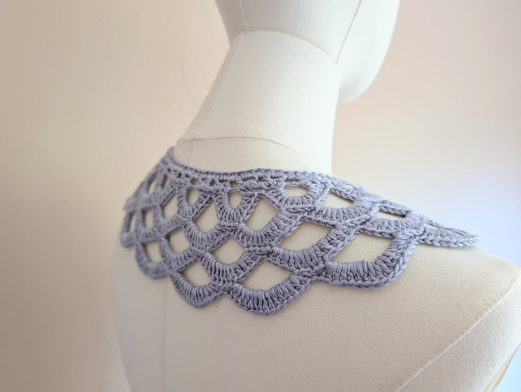 Detailed view of the crochet collar's top edge, showing a neatly finished neckline border and long half-double crochet ties fastened into a soft bow at the front.