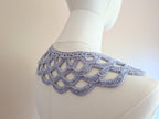 Detailed view of the crochet collar's top edge, showing a neatly finished neckline border and long half-double crochet ties fastened into a soft bow at the front.