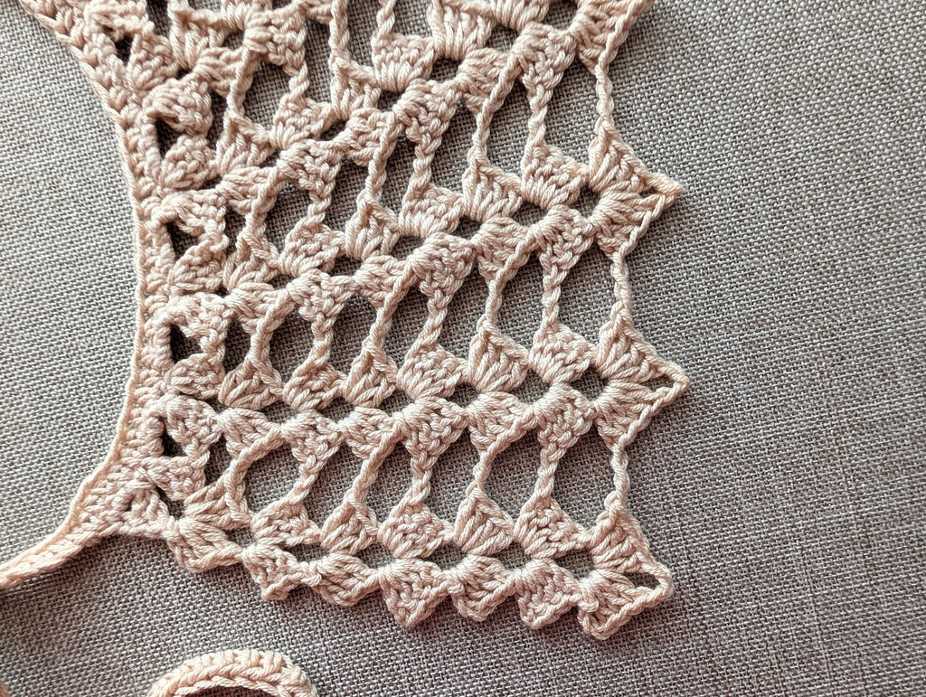 Close-up view of the neat single crochet neckline border and half double crochet tie bow.