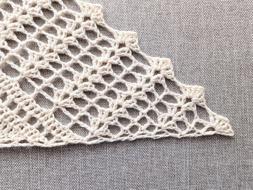 Close-up shot of the decorative scalloped shell border along the edge of the crochet triangle shawl.