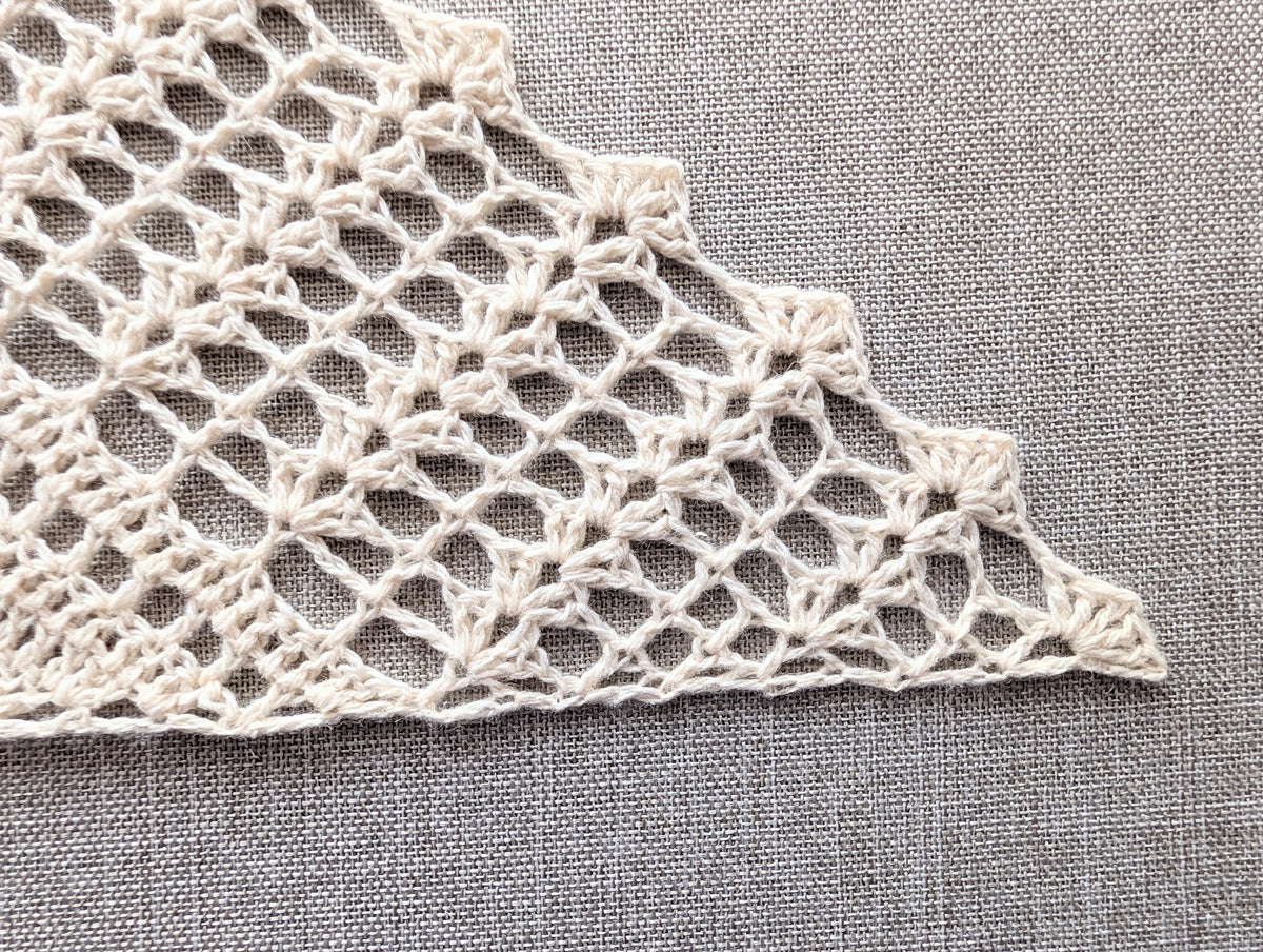 Close-up shot of the decorative scalloped shell border along the edge of the crochet triangle shawl.