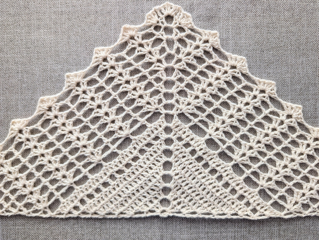 Detailed close-up of textured double crochet shell stitches and solid rows in a handmade crochet triangle shawl.