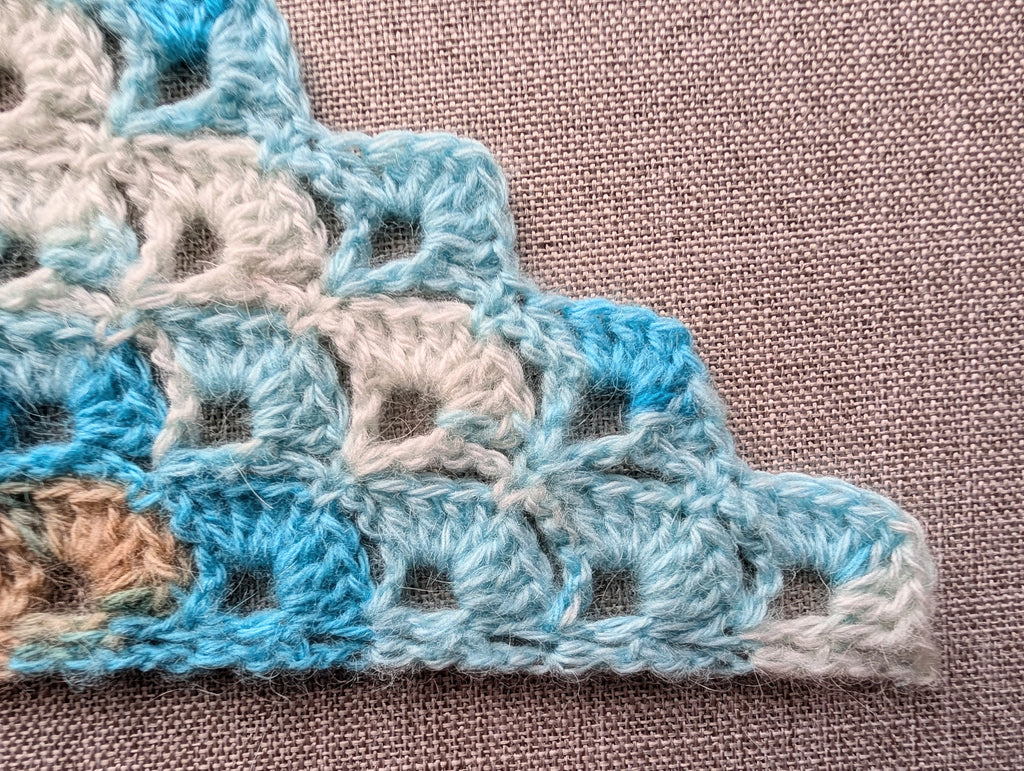 Close-up of double crochet shell stitches forming a dense 2-row repeat pattern without a border.