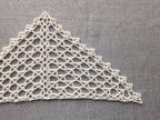 Close-up detail of the delicate scalloped shell border along the edge of the mesh crochet shawl.