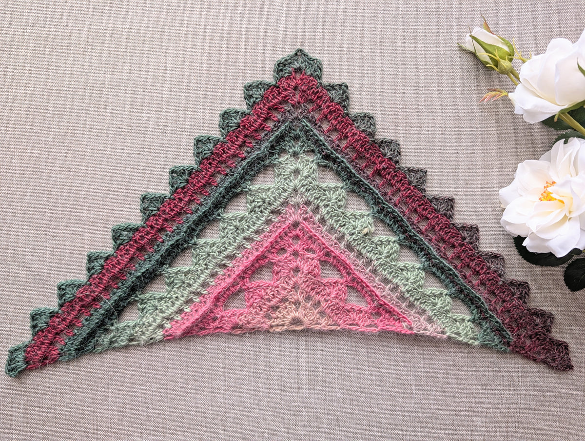 Full view of an advanced textured triangle shawl crochet pattern #112 worked in gradient color-changing cake yarn.