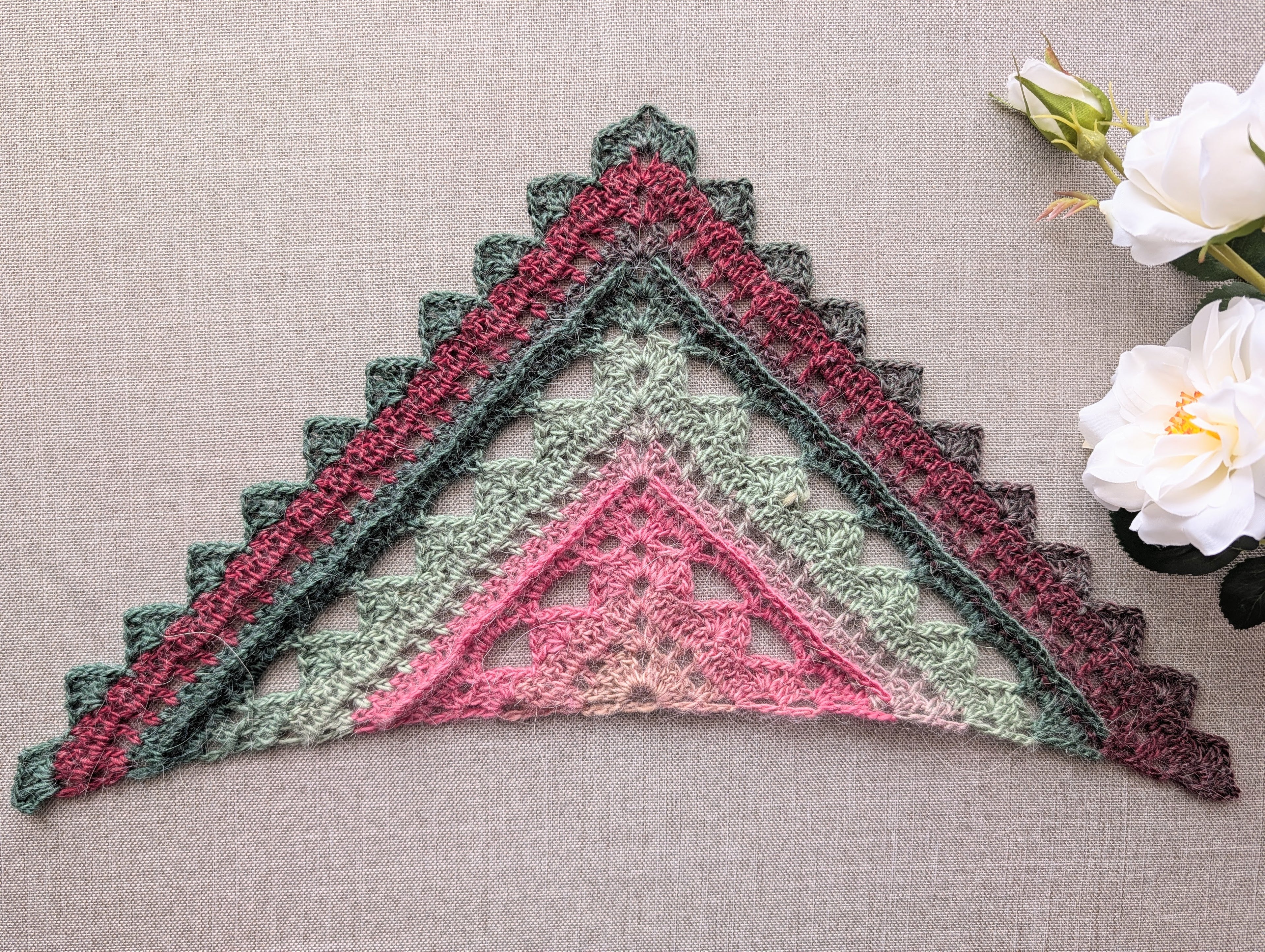 Full view of an advanced textured triangle shawl crochet pattern #112 worked in gradient color-changing cake yarn.