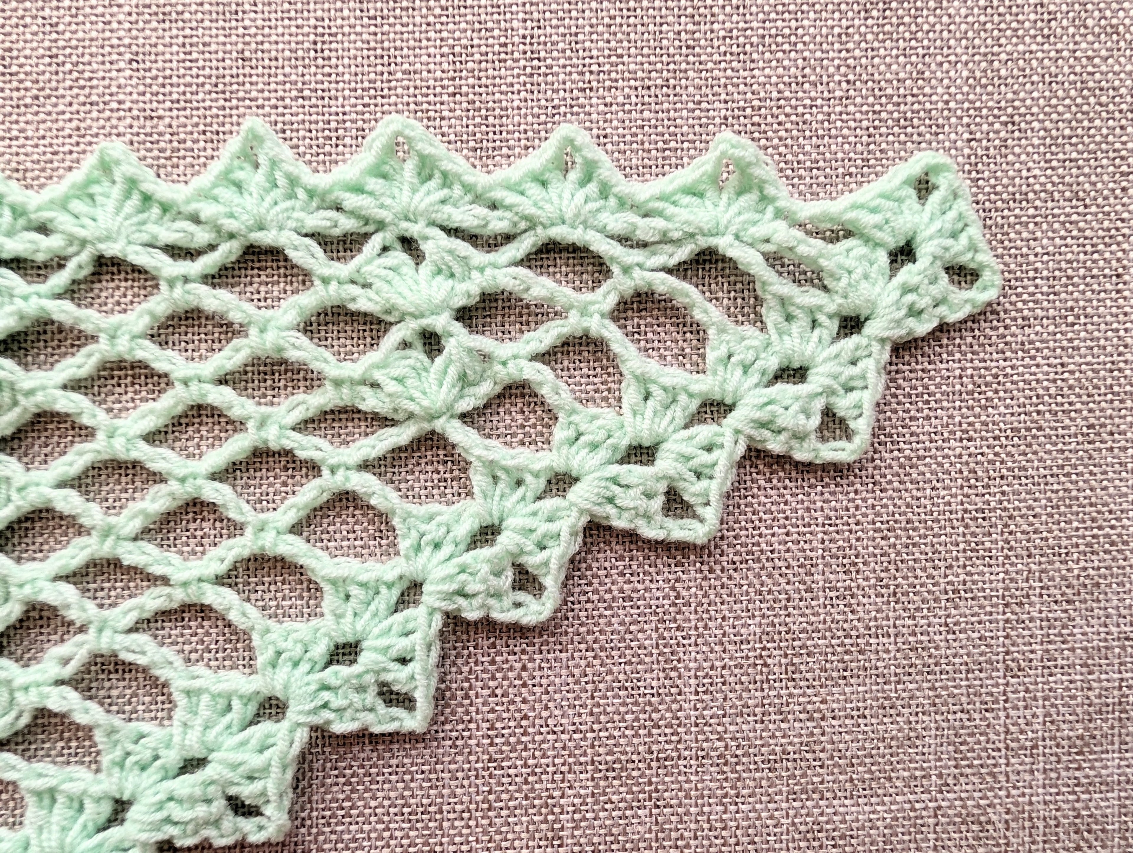 Close-up detail of the intermediate crochet pattern stitches, highlighting the textured 3-dc clusters and the defined chain-space lace texture.